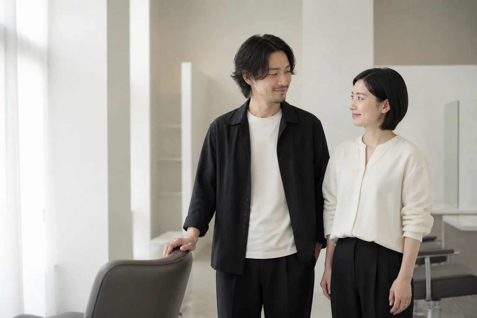 明るいサロンで穏やかに笑い合う、オーナーらしき女性とスタッフらしき男性の2ショット
